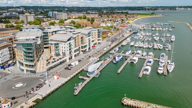A marina with boats docked, a waterfront promenade, and modern buildings. - Jibe Ho - Spacious Apartment with Harbour Views (Poole)