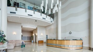 A spacious lobby with a reception desk, a curved ceiling, and a glass railing overlooking a lower level. - Jibe Ho - Spacious Apartment with Harbour Views (Poole)