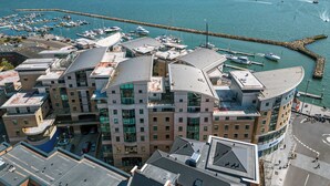 A modern hotel with a curved roof, located near a marina with boats. - Jibe Ho - Spacious Apartment with Harbour Views (Poole)