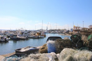A marina with boats docked, fishing nets, and a crane in the background.