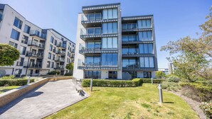 A modern multi-story residential building with balconies, a paved walkway, and a well-maintained lawn. - Sea Breeze - Close to Bournemouth Beach (Bournemouth)