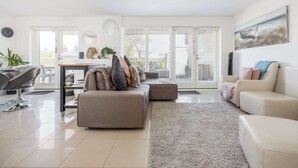 A modern living room with a sofa, a coffee table, and a dining area with a table and chairs. - Sea Breeze - Close to Bournemouth Beach (Bournemouth)
