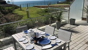 An outdoor dining area with a table set for four, overlooking a scenic view of the ocean. - Sea Breeze - Close to Bournemouth Beach (Bournemouth)