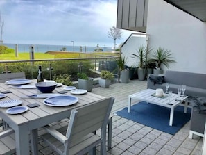 Un patio al aire libre con mesa lista para comer, un sofá y plantas en macetas.