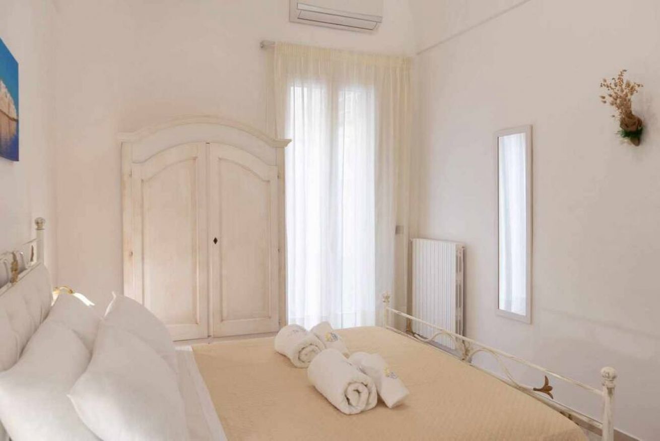 Une chambre à coucher avec un lit, un radiateur, une fenêtre avec des rideaux et une porte.