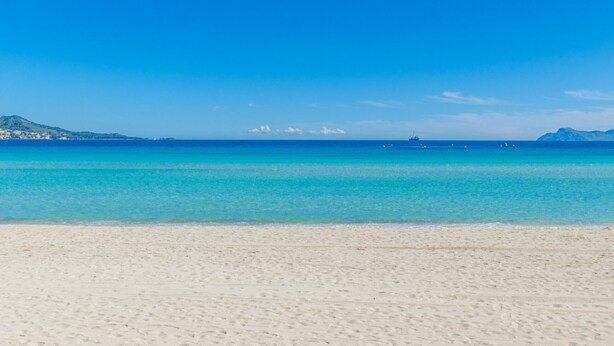 Une plage avec une eau turquoise cristalline et un rivage sablonneux.