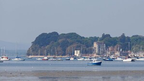 A coastal scene with numerous boats docked along the shore, a sandy beach, and a large building with a tower in the background.