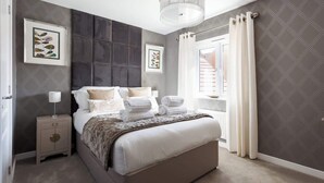 A neatly arranged bedroom with a bed, bedside tables, a lamp, and artwork on the walls.