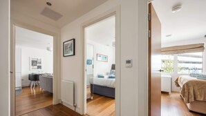 A modern apartment with a wooden floor, a dining area, a bedroom with a bed and window, and a living area with a sofa. - Castle Lanes - Minutes from Poole Quay (Poole)