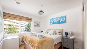 A bedroom with a bed, bedside table, nightstand, and a window with a view of trees and buildings. - Castle Lanes - Minutes from Poole Quay (Poole)