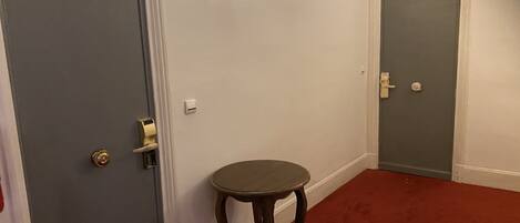 A hallway with two grey doors, a small round table, and a red carpet.