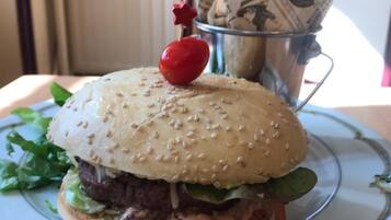 A hamburger with a cherry tomato on top, served on a decorative plate.
