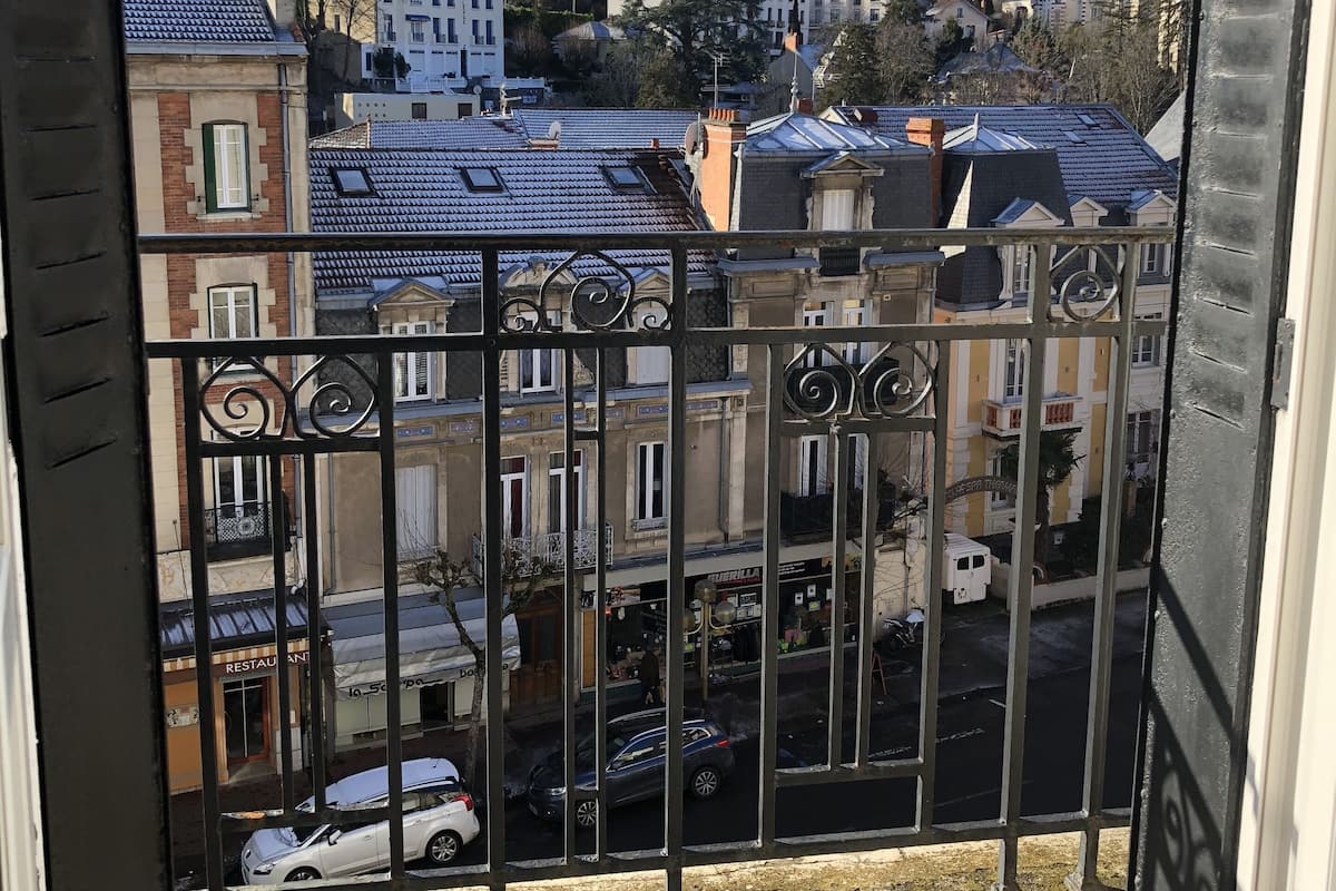 A balcony with a view of a cityscape, including buildings and parked cars.