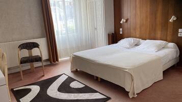 Un dormitorio con cama, una silla, un tapete y una ventana con cortinas.