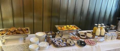 A buffet table with various food items and condiments.