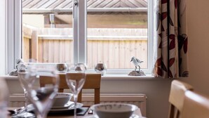 A dining table set for two with a view of a wooden deck through a window. - Sanderling - Close to Poole Quay and Baiter Park (Poole)