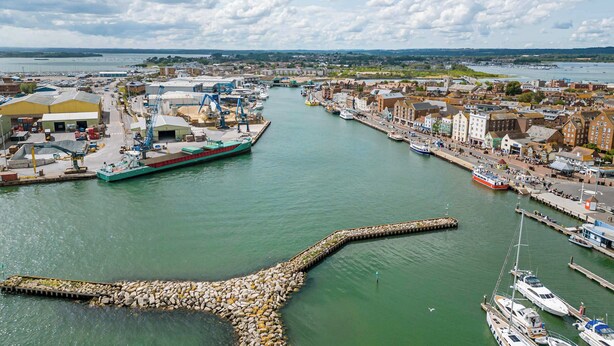 A harbor with boats, a large green ship, and industrial buildings. - Marina Secret - with Free Parking (Poole)