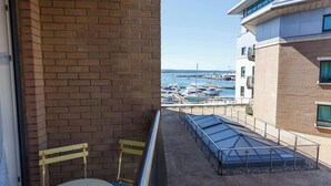 A balcony with a view of a marina, a brick wall, and a metal railing. - Marina Secret - with Free Parking (Poole)