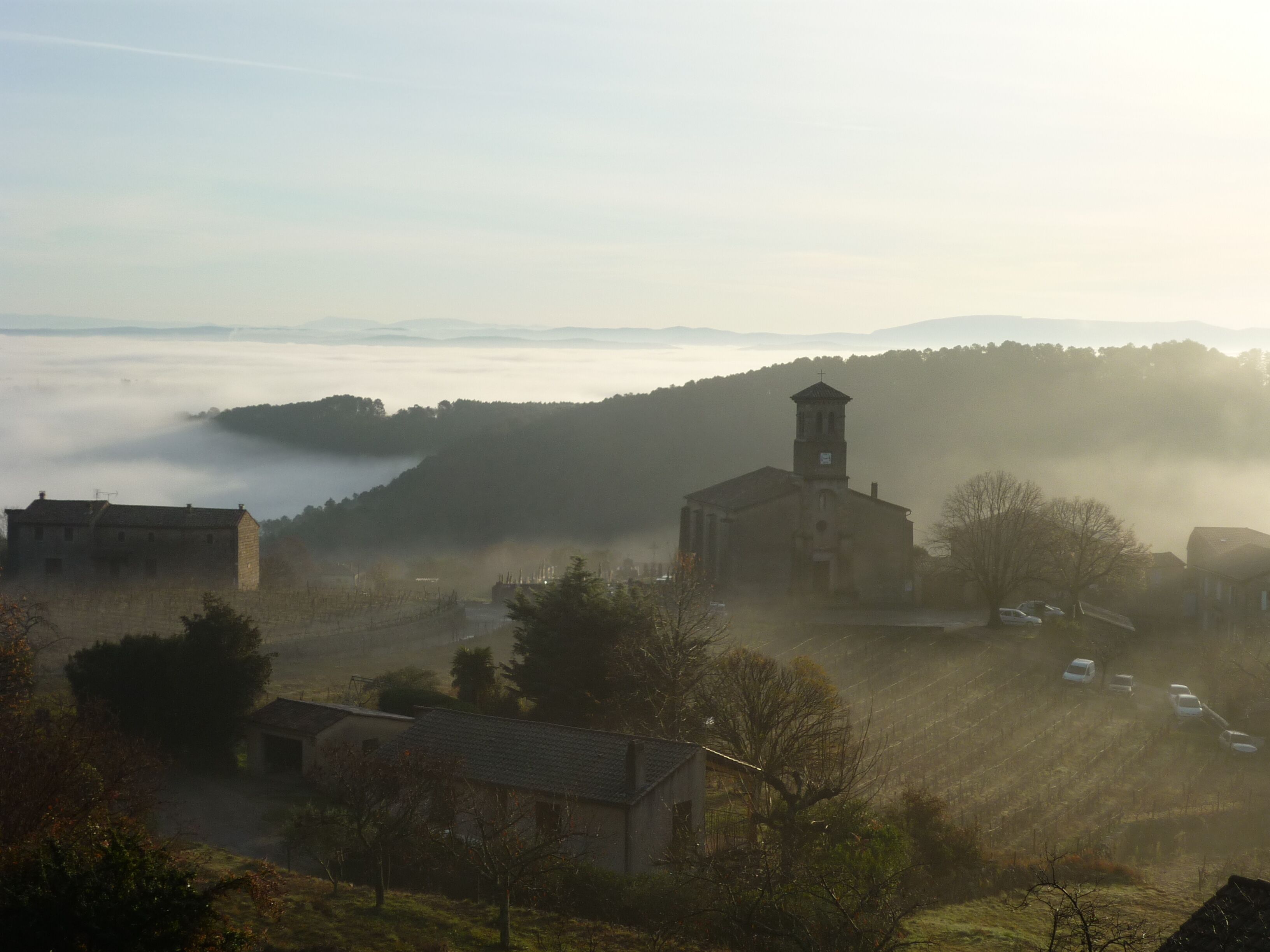 A rural village with a prominent church featuring a bell tower, surrounded by houses and fields.