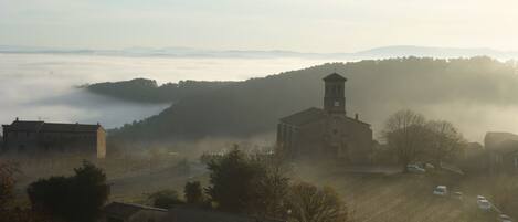 A rural village with a prominent church featuring a bell tower, surrounded by houses and fields.