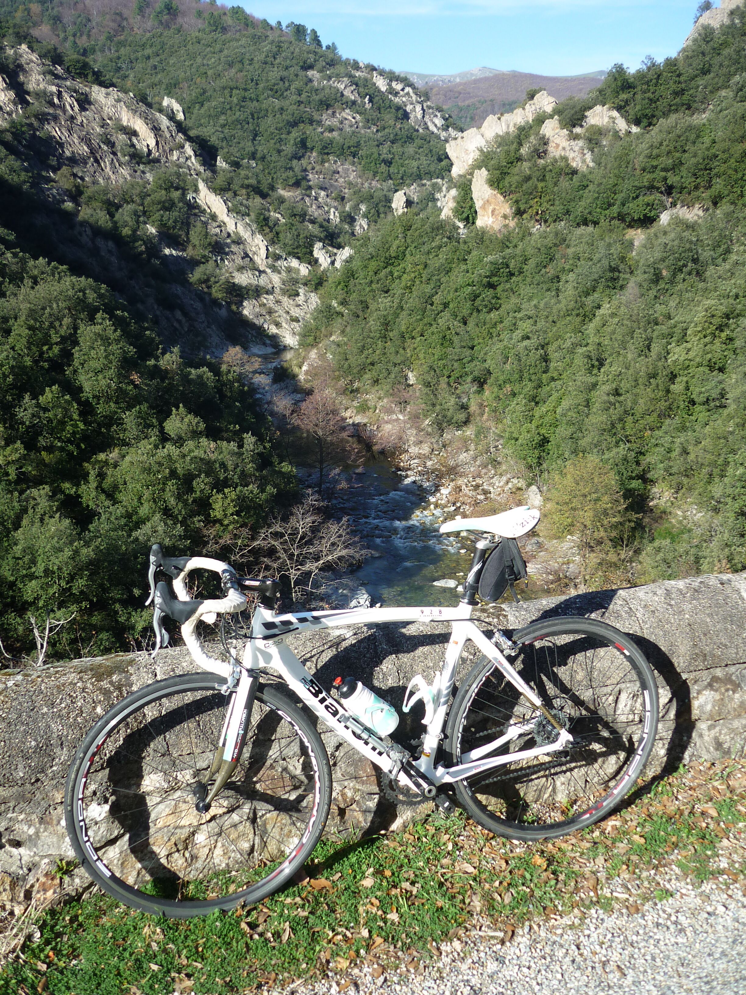 Ein Fahrrad, das auf einer felsigen Klippe mit Blick auf einen Fluss und ein bewaldetes Tal abgestellt ist.