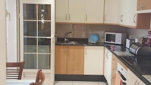 Eine Küche mit Holzausstattung, einem Spülbecken, einer Mikrowelle und einem Essbereich mit Tisch und Stühlen.