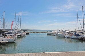 Een jachthaven met verschillende boten afgemeerd, een houten steiger en een heldere lucht.