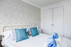 A hotel room with a bed, pillows, a nightstand, a lamp, and a wardrobe. - Palma - Coastal Home near Harbour and beach (Poole)