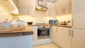 A modern kitchen with white cabinets, a microwave, an oven, and a sink. - Curlew - In the Heart of Poole Town (Poole)