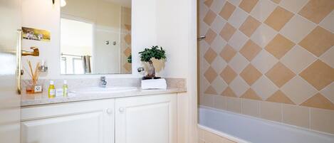 Un baño con lavabo, espejo y zona de ducha.