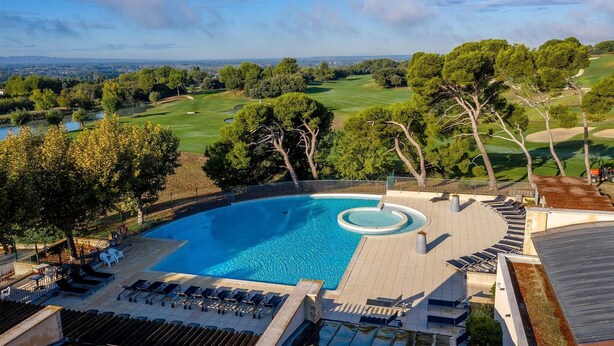 Ein Pool auf dem Dach mit Blick auf einen Golfplatz und umliegende Bäume.