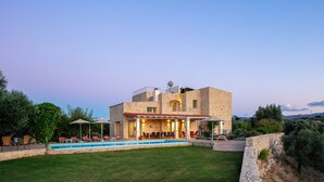 Ein zweistöckiges Steinhaus mit Swimmingpool, Sitzgelegenheiten im Freien und Blick auf die umliegende Landschaft.