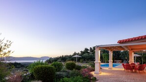 Ein überdachter Außenbereich mit Pool, roten Stühlen und einer Pergola.