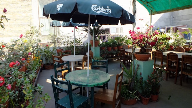 An outdoor patio area with tables and chairs, surrounded by potted plants and flowers. - Hotel Dolphin (Kathmandu)