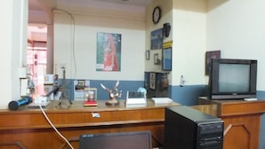 A reception desk with a computer, a clock, and various decorative items. - Hotel Dolphin (Kathmandu)