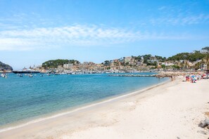 A coastal beach with clear waters, a sandy shore, and buildings in the background. - Renovated 2026! Air-Conditioned Apartment with Seaview, shared pool and Wi-Fi in Port de Sóller (Port de Soller)