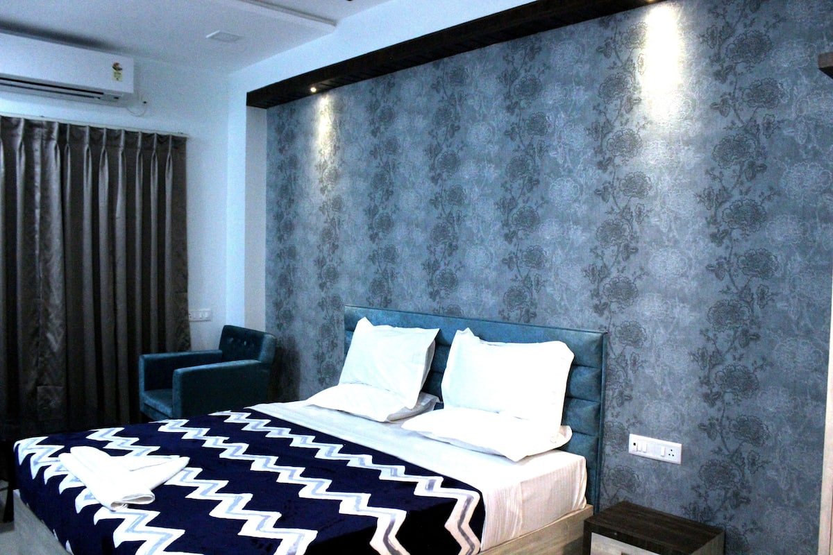 Une chambre d’hôtel moderne avec un grand lit, une chaise et un climatiseur fixé au mur.