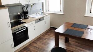 Eine moderne Küche mit weißen Schränken, einer Holz Arbeitsplatte, einem eingebauten Backofen und einem Fenster mit Vorhängen.