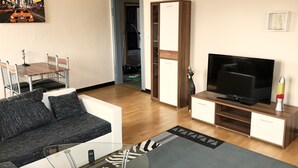 Ein modernes Wohnzimmer mit einer Couch, einem Fernseher und einem Glastisch.
