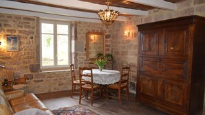 A room with a stone wall, wooden furniture, a chandelier, and a large cabinet. - Small rustic cottage with terrace u. Hochgarten in outskirts (Tignécourt)