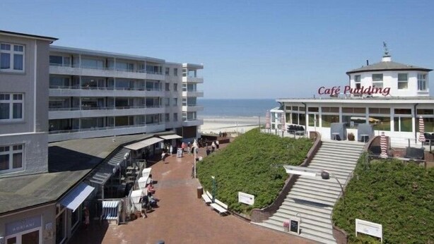 En byggnad vid kusten med ett kafé som heter ”Café Pudding” och utsikt över stranden.
