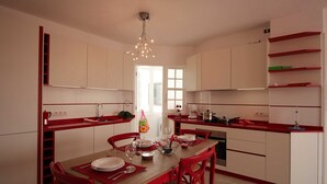 Une cuisine moderne avec des meubles blancs, des touches de rouge et un îlot central.