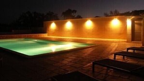 Una piscina con cubierta de baldosas y una pared con luces.