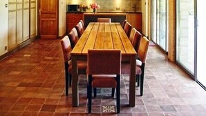 Una cocina espaciosa con vigas de madera, una mesa de comedor grande y abundante luz natural proveniente de amplias ventanas.
