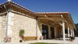 Un edificio de piedra con techo de tejas y un patio cubierto.
