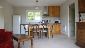 A compact kitchen with a dining table, chairs, a refrigerator, and a microwave. - Domaine du Vernadel, Panoramic, swimming pool near Antraiques and Vals les Bains (Asperjoc)