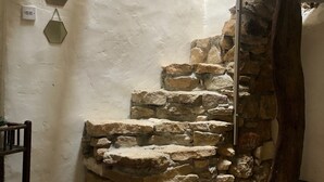 Eine Steintreppe, die zu einer höheren Ebene führt, ein rustikaler Holzstuhl und eine Wandleuchte.