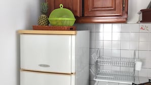 Una cocina con armarios de madera, un refrigerador blanco, un lavamanos de acero inoxidable y una estufa a gas.