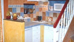 A kitchen with a tiled backsplash, white cabinets, and a microwave on the countertop.