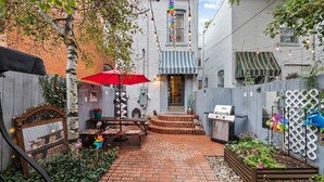 A backyard with a brick patio, a barbecue grill, and a small table with a red umbrella. - The Arusha House Capitol: Hill : Garage : Yard (Denver)